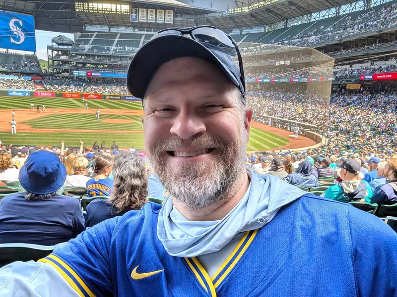 Selfie in a blue Mariners jersey at a crowded baseball stadium