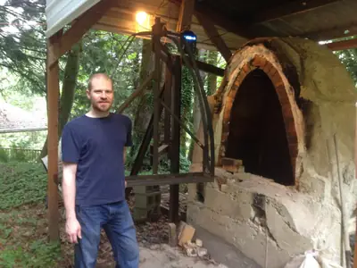 Aaron Filson standing beside the soda kiln and its new steel door frame